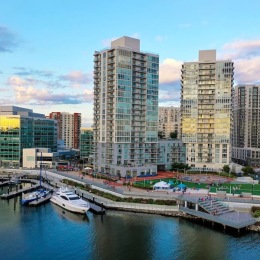a city with tall buildings and boats in water